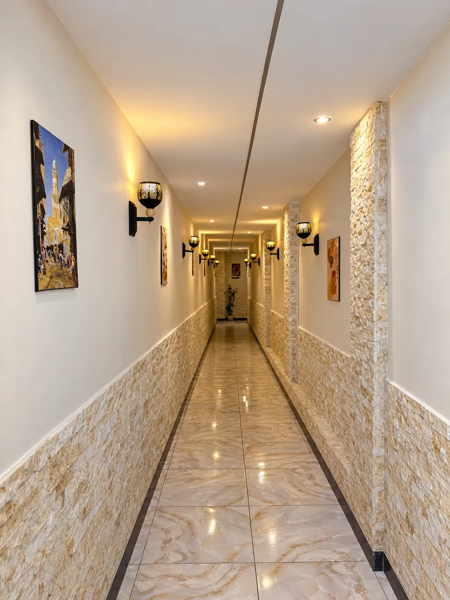 Hotel corridor with stone clad walls, warm wall lanterns and paintings of old Cairo