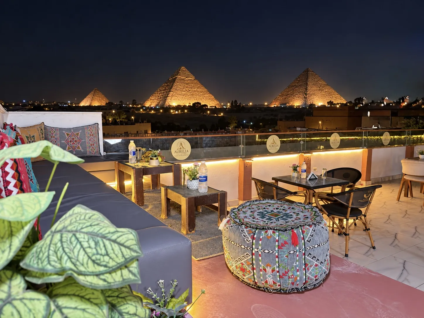 Rooftop lounge of Aurelia Pyramids at night facing the three illuminated Pyramids of Giza