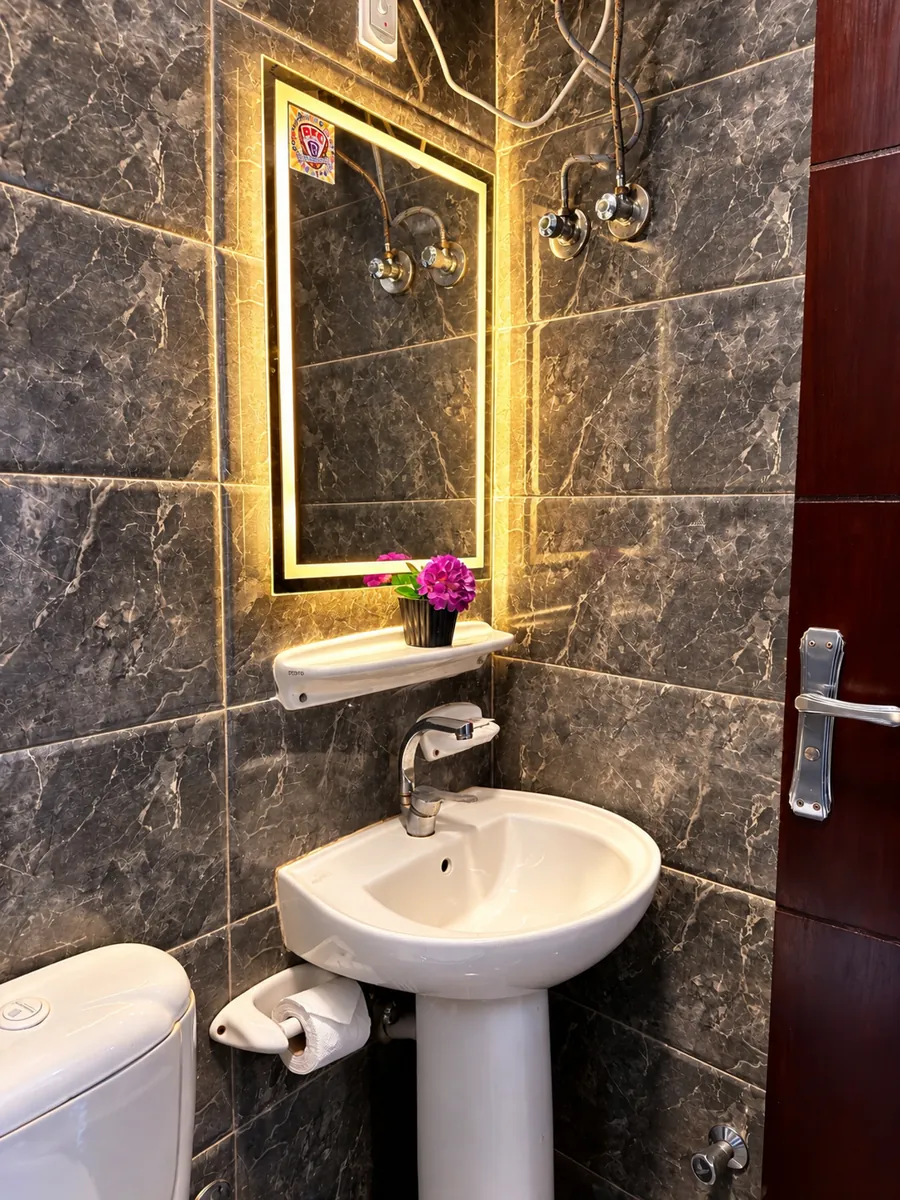 Bathroom of room 201 with illuminated mirror, washbasin and dark marble effect tiles