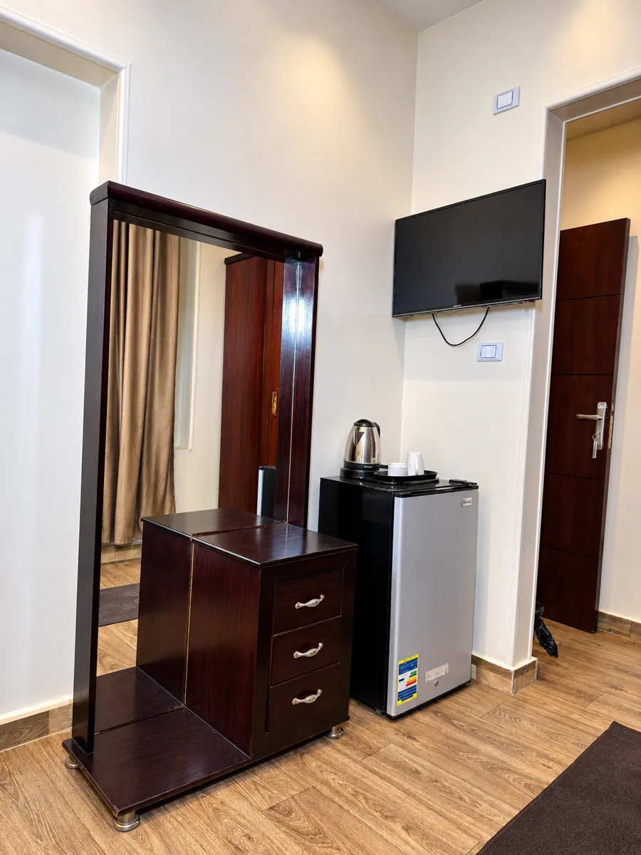Dresser with mirror, refrigerator, electric kettle and wall mounted TV in room 201
