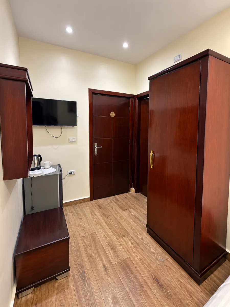 Entrance area of room 202 with wardrobe, wall mounted TV, refrigerator and electric kettle