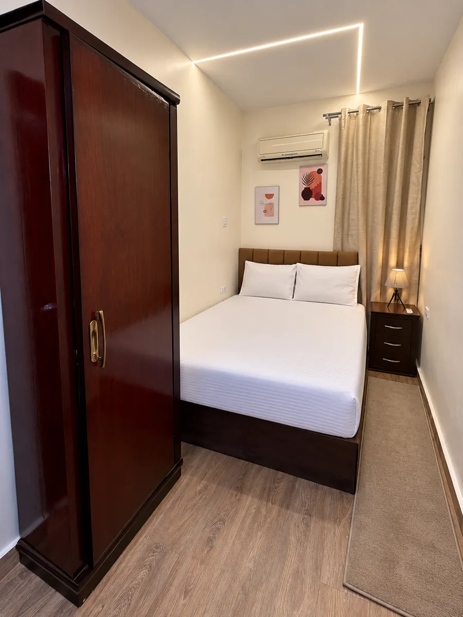 Room 202 with double bed, padded headboard, bedside lamp, curtained window and tall wardrobe