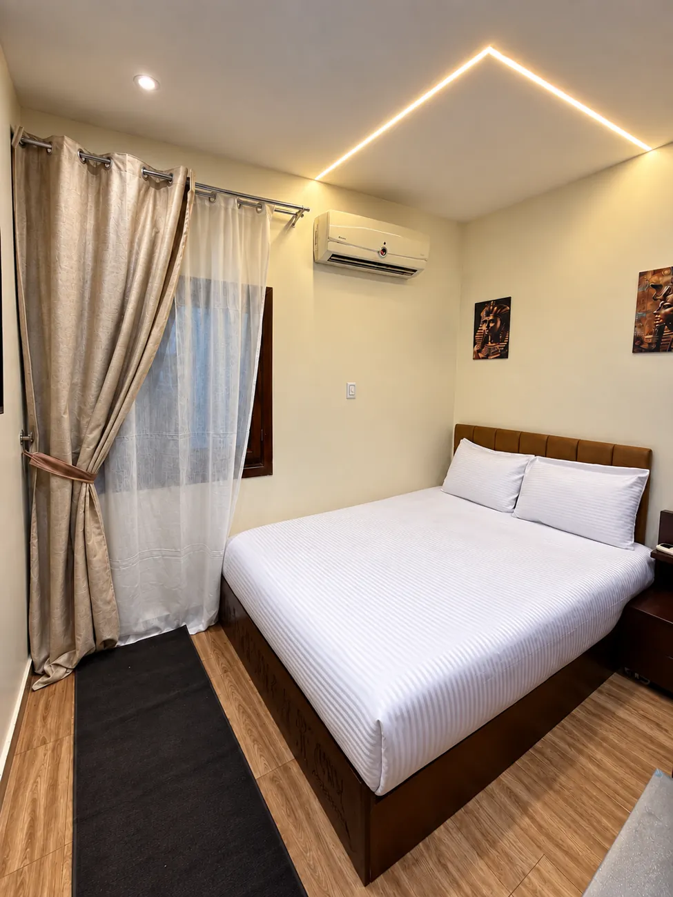Room 203 with double bed, padded headboard, curtained window and warm ceiling light