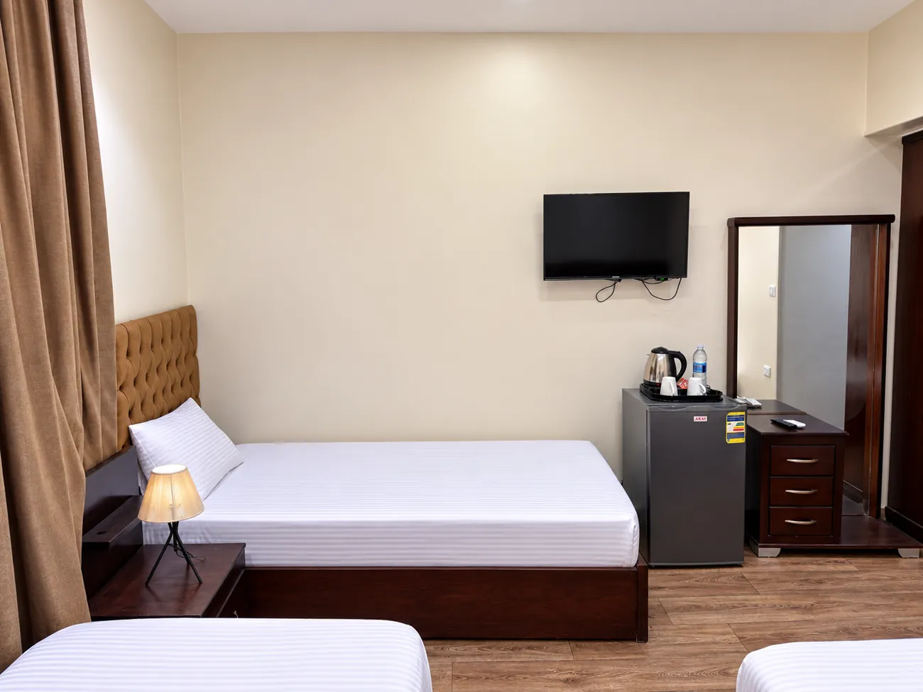 Single bed, wall mounted TV, refrigerator with kettle and dresser with mirror in room 205