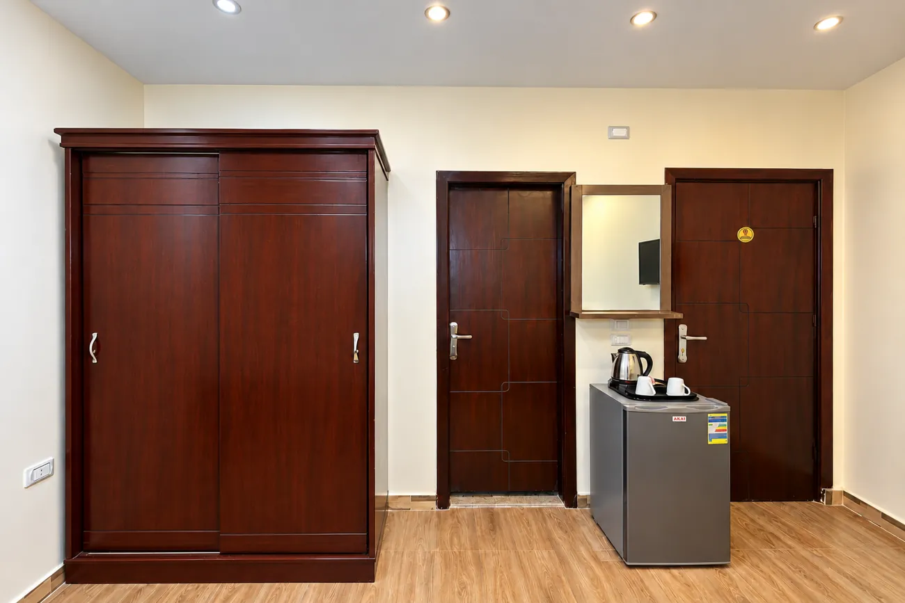Room 206 with sliding wardrobe, refrigerator with kettle, mirror and the entrance and bathroom doors